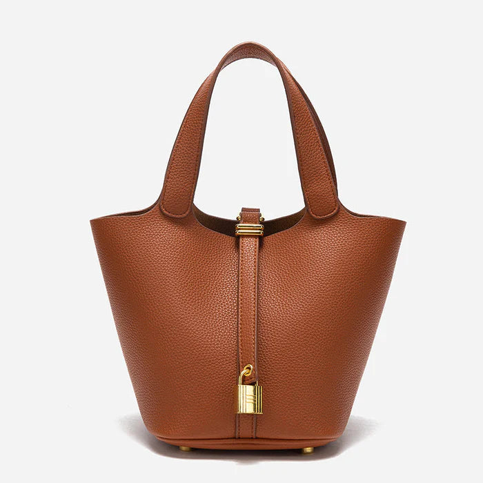 Spacious bucket tote with structured leather body, adjustable shoulder strap, drawstring closure, and minimalist design for everyday carry