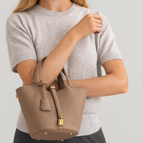Spacious bucket tote with structured leather body, adjustable shoulder strap, drawstring closure, and minimalist design for everyday carry