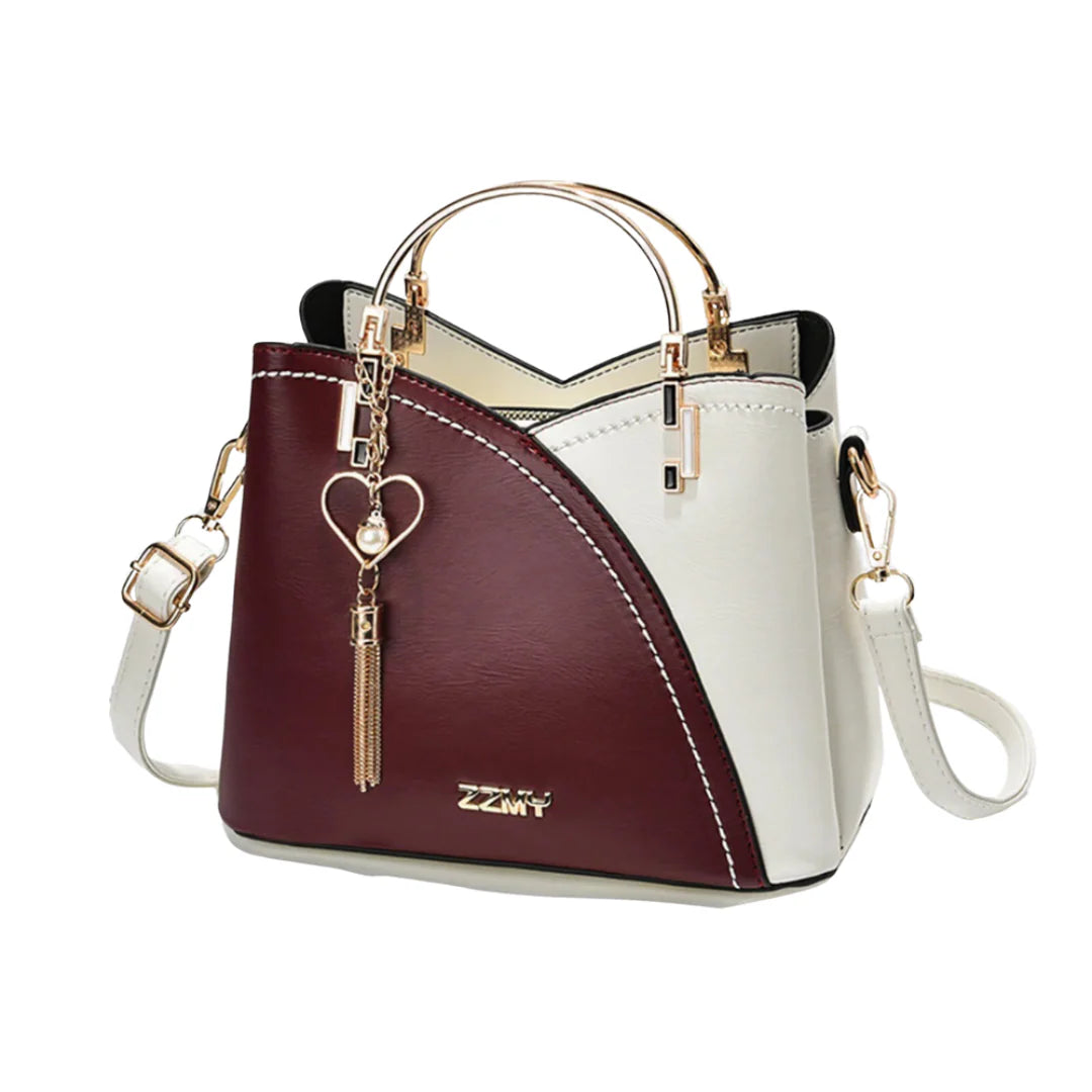 Ivory and taupe two-tone faux leather tote bag with gold-tone hardware, dual top handles, detachable crossbody strap, and heart-shaped charm with pearl accent.