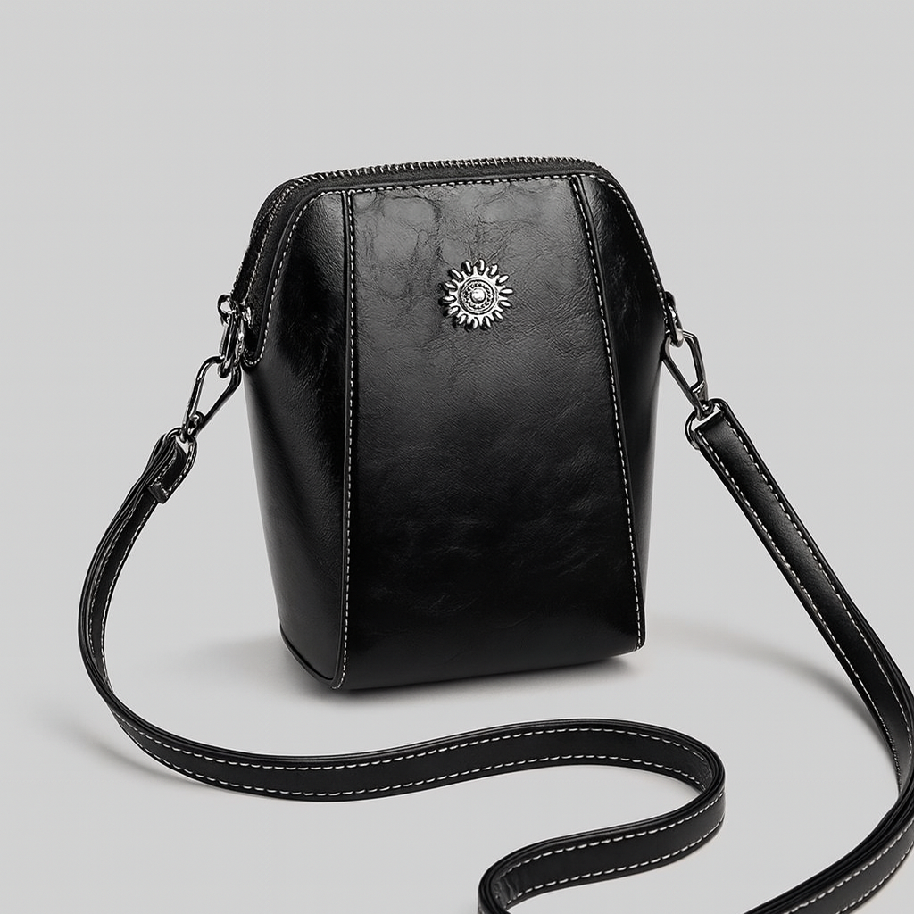 Compact crossbody bag with sleek leather finish, adjustable strap, secure top zip closure, and minimalist design for everyday use