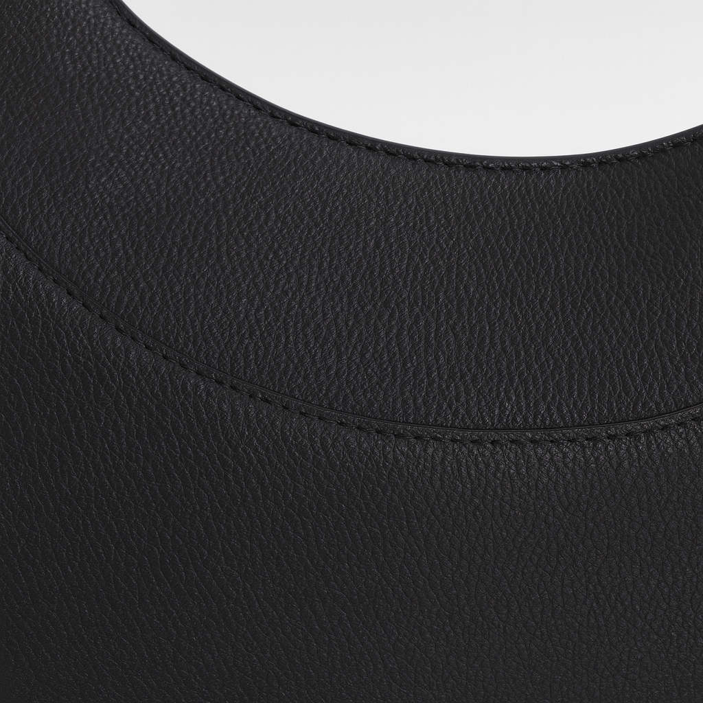 Faux leather crescent shoulder bag with curved silhouette, adjustable strap, and gold-tone zipper closure.