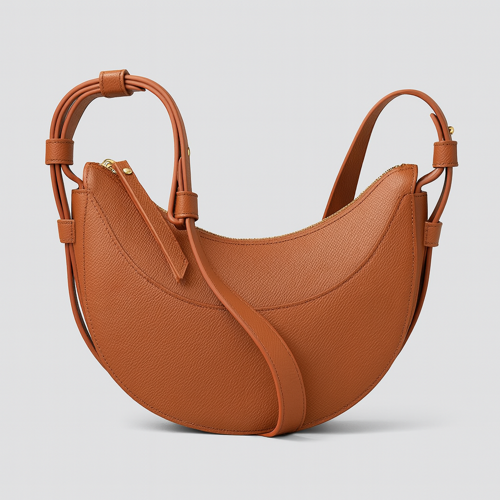 Faux leather crescent shoulder bag with curved silhouette, adjustable strap, and gold-tone zipper closure.