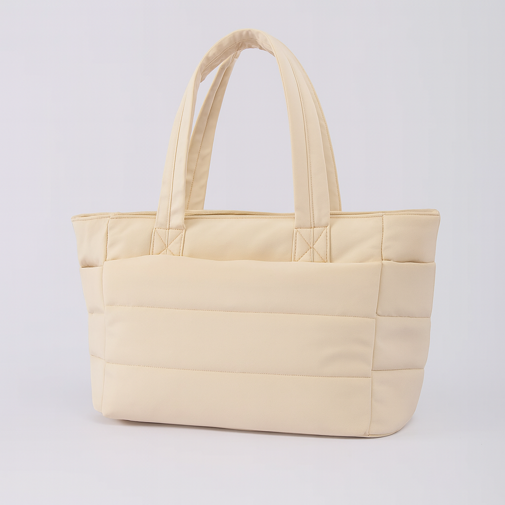 Quilted tote bag with a spacious main compartment, soft padded design, and sturdy shoulder straps for daily use.