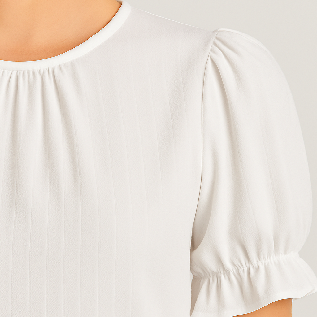 White puff sleeve blouse with round neckline and ruffle cuffs.